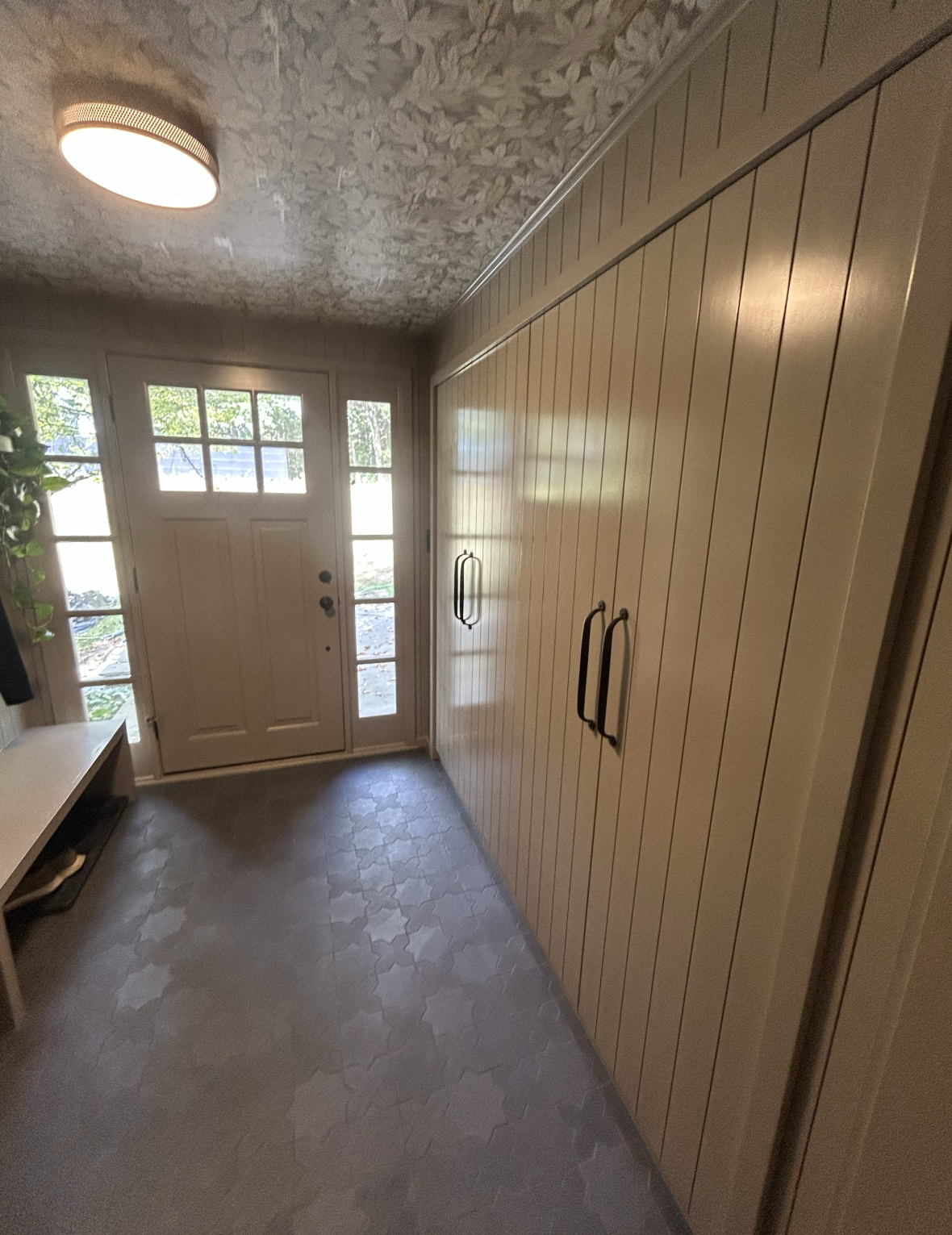 Bright entryway with wooden wall panels and large windows.