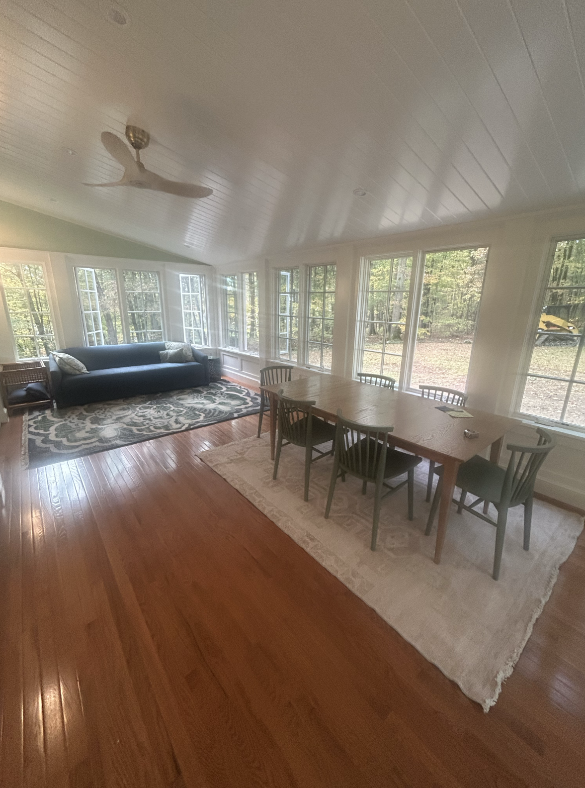 Bright dining and living area with large windows and wooden floors.